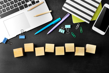 Laptop, copybook and wooden cubes on color background