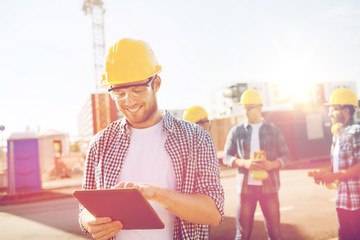 smiling builders in hardhats with tablet pc