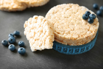 Round rice crispbreads with blueberries and measuring tape on table, closeup