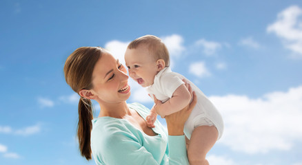 happy young mother with little baby over blue sky