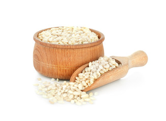 Brown short grain rice in wooden bowl and scoop on white background