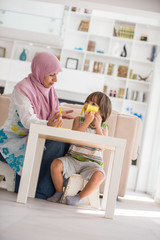 Arabic mother with little son learning in living room