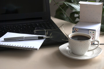 Blank notepad over laptop and coffee cup. Work desk with laptop computer and hot coffee cup with defocused background