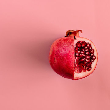 Red pomegranate fruit on pastel pink background. Minimal flat la