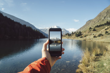 France, Pyrenees, Pic Carlit, man taking a picture at mountain lake