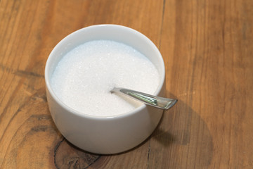 White sugar in glass bowl with teaspoon
