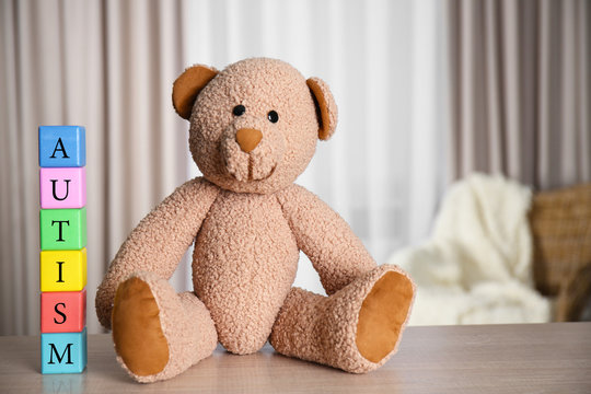 Colorful wooden cubes with Teddy bear on curtains background. Autism concept
