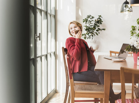 Smiling young woman using cell phone in a cafe