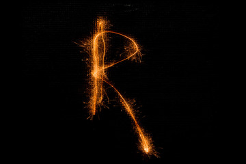 Letter R made of sparklers on black