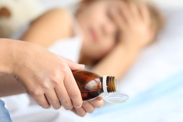Woman pouring syrup for sick girl