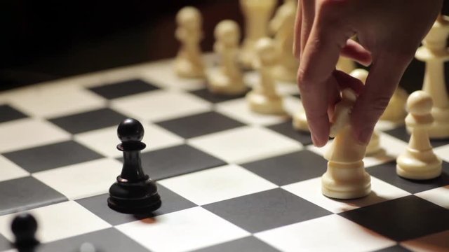 Panoramic footage of a chess match, with white knight capturing the black pawn.