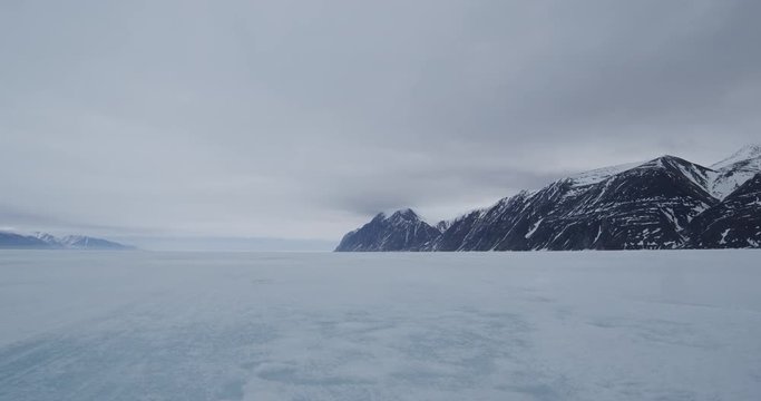 Pan across river of sea ice from mountain range to mountain range