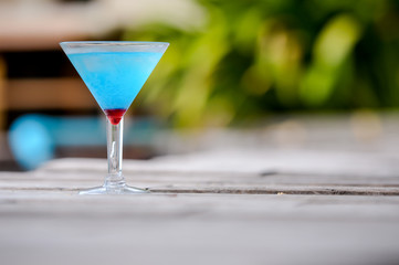 Frozen Blue Margarita Cocktail, blue cocktail on the wooden table, blurry background