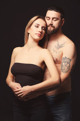 Fototapeta na wymiar Portrait of romantic tattooed couple on black background