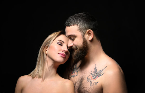 Portrait of romantic tattooed couple on black background