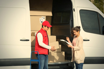 Young woman signing receipt for delivering parcel from male courier