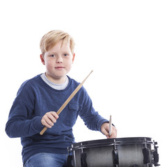 young blond boy plays drum against white background