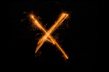 Letter X made of sparklers on black