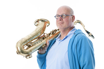 middle aged man carries tenor saxophone on shoulder against whit