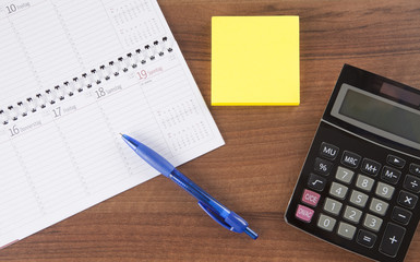 Workplace in office with calendar, pen, calculator and post it