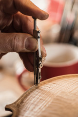 violin maker working with dividers on violin body