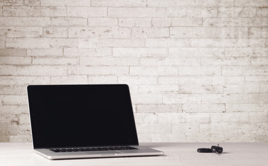 Business laptop with white brick wall