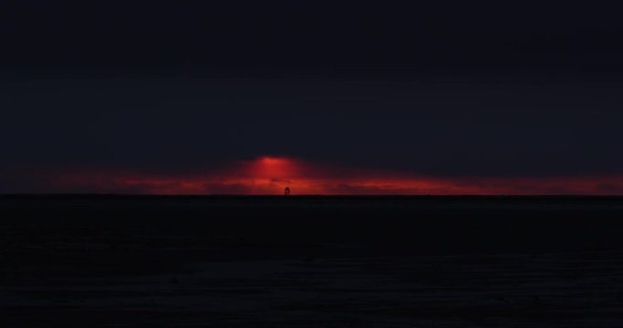 Wide scenic arctic sunset with tower on horizon of red sky