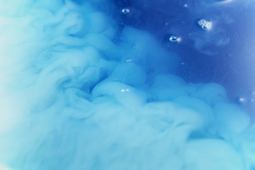 blue and white inks mixing together from above, abstract background