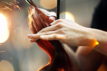 Hairdresser cutting and modeling brown hair by scissors and comb