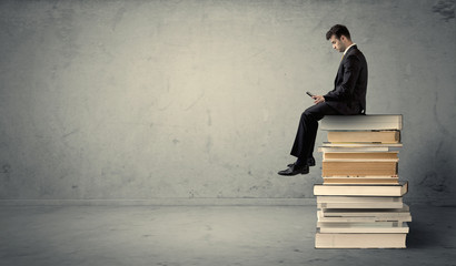 Man with laptop sitting on books
