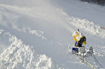 Fototapeta na wymiar Yellow snow maker machine (snow gun, snow cannon) at ski slopes