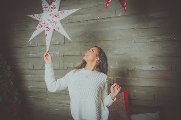 attractive girl in white sweater in bed playing with star decoration.