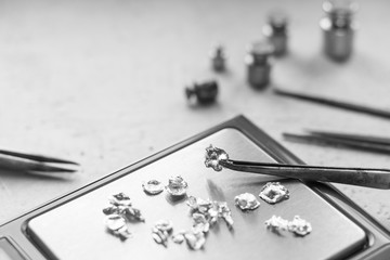 Jewelry tools. Jewellery. Goldsmith workplace, workspace on light background. Hand craft. Workshop. Manufacturing. Weigh-scales with granules of metal silver and platinum. Closeup. Toned