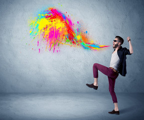 Fototapeta premium Hipster guy shouting colorful paint on wall