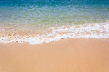 Fototapeta na wymiar Strandsand im Sommer mit türkis-blauem Wasser.