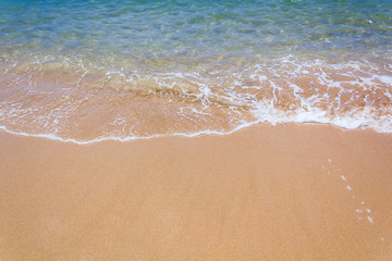 Strandsand im Sommer mit türkis-blauem Wasser.