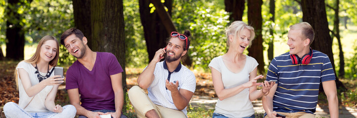 Fototapeta premium Friends in park with smartphones