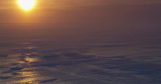 Beautiful sunset glare on sea ice with blizzard blowing snow