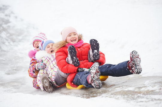 children having fun riding ice slide in winter