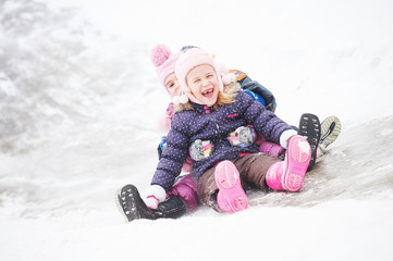 Fototapeta na wymiar children having fun riding ice slide in winter
