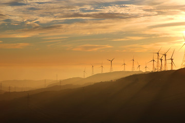 Wind turbines during sunset with Andalusian hills, Atlantic ocean and mountain of Africa on background.