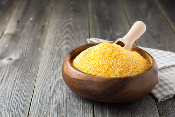 Raw corn grits polenta in a bamboo bowl on the old wooden background. Selective focus © kasia2003
