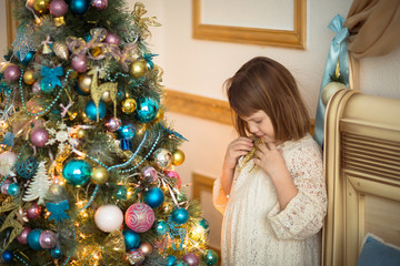 Girl kid in dress with  bear around  Christmas tree,  real inter