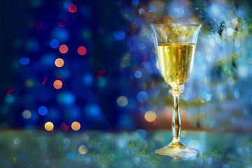 festive atmosphere in the evening with a glass of champagne and  bokeh. Christmas, New Year's atmosphere. soft focus,  Blurred image of a Christmas tree with garlands of lights.
