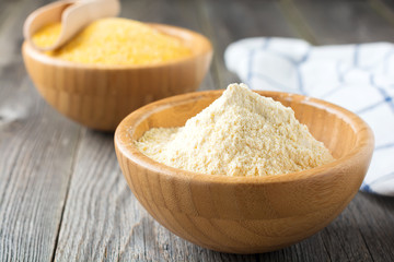 Raw corn meal and grits, polenta in a bamboo bowl on the old wooden background. Selective focus.