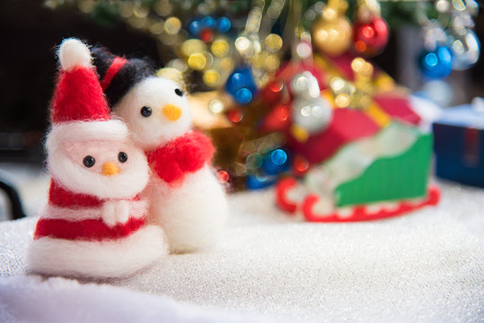 Santa claus and snowman wool doll on snow set up with xmas tree,