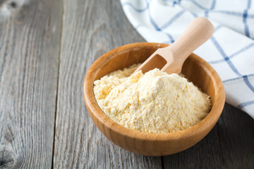 Raw corn meal and grits, polenta in a bamboo bowl on the old wooden background. Selective focus.
