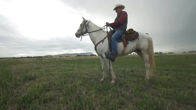 Senior cowboy on Horse Uses Cell Phone- Dolly Left