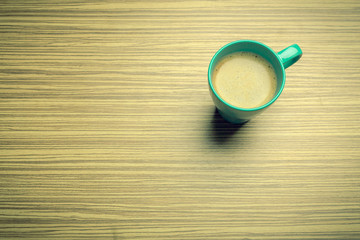 Cup of coffee on wooden table, top view