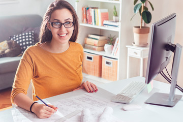 Smiling young woman architect in home office